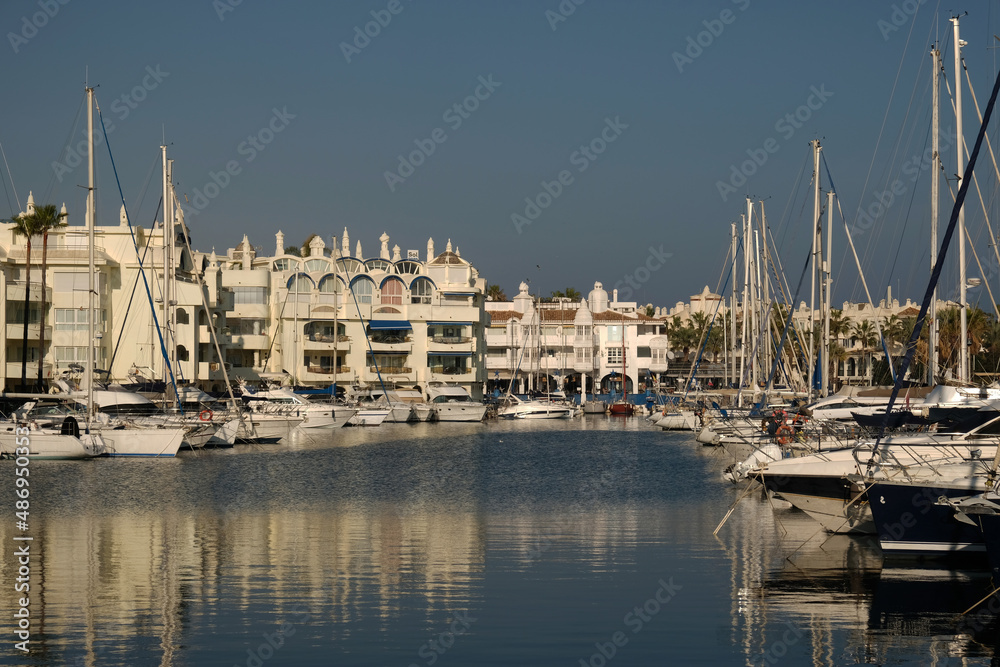 Boats in a yacht club in the Mediterranean sea, Malaga, Spain. Yachts moored in the port on sunny day, Reflection in water.