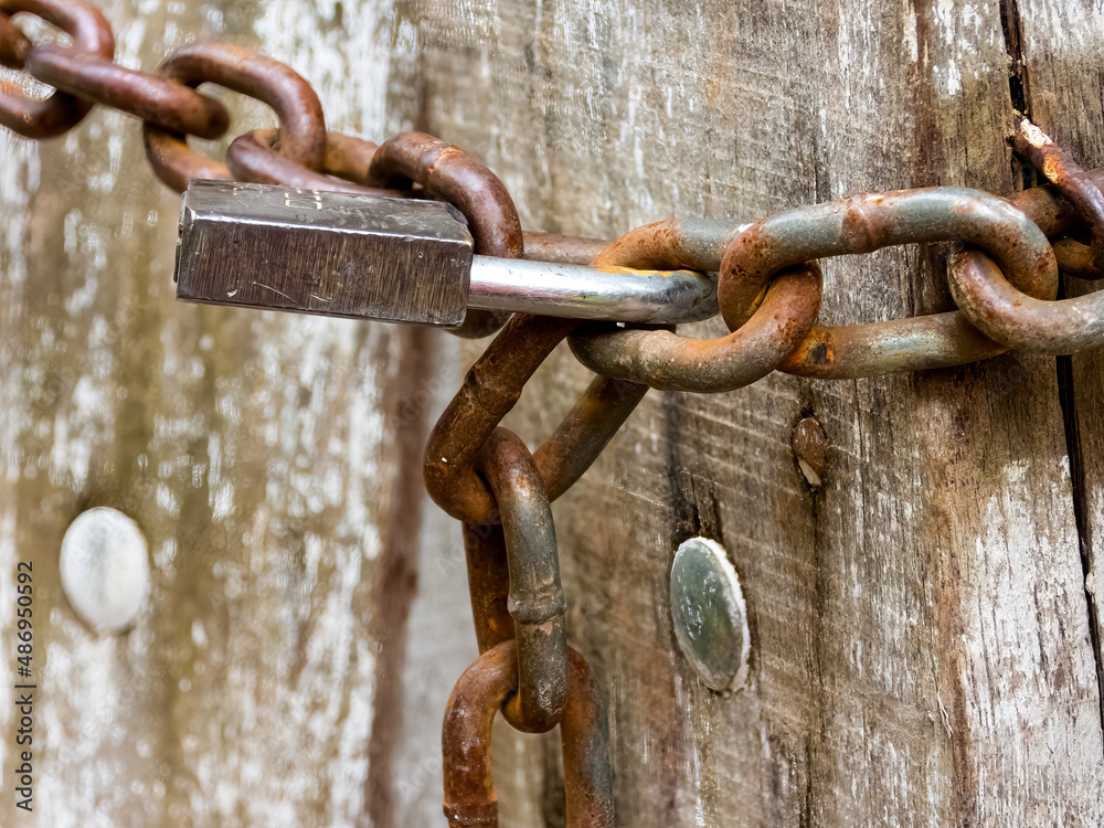 Detail of a closed wooden gate with padlock and chains Detail of a closed wooden gate with padlock and chains
