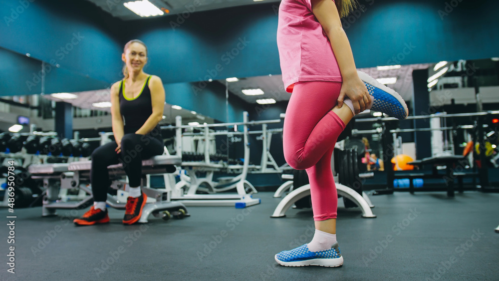 Mother and Daughter in the Gym, Family Performs Physical doing Exercises Fitness, Healthy Lifestyle. Happy Sports Family Training Concept. Woman with her Child doing Stretching Warm-up in the Gym
