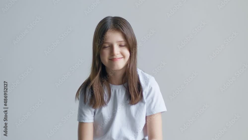 Blonde teenager girl in a white t-shirt nods and agrees and says yes against a white wall Blonde teenager girl in a white t-shirt nods and agrees and says yes against a white wall