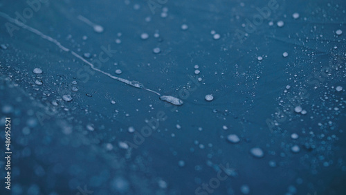 Close-up shot of raindrops water droplets on the tent. Dew drops on texture of fabric of tourist tent in rays of rising or setting sun. Camp, hiking tourism. The rain is pounding on tent.