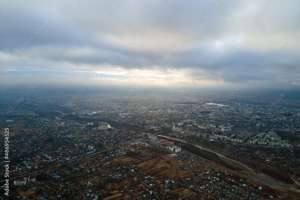 Aerial view of rural homes and distant high rise apartment buildings in city residential area during cloudy weather
