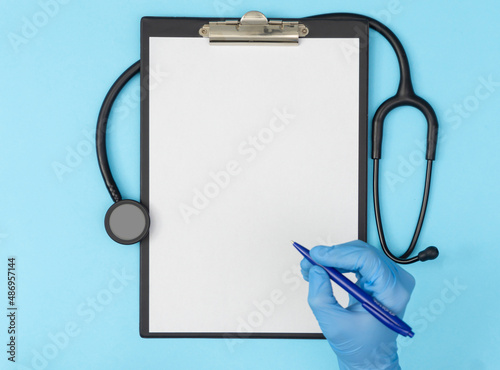 A tablet with a blank page on a blue background with hand. Medical diagnosis or a mock-up of a doctor's prescription.
