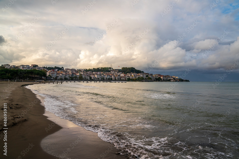 Beach with city view at sunset, cloudy sky