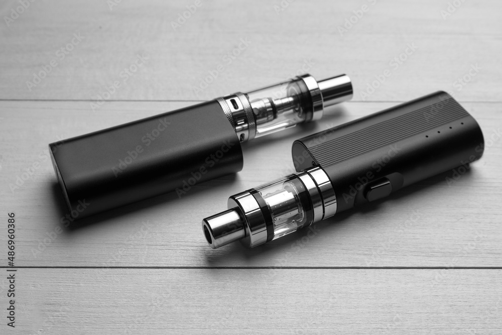 Two electronic cigarettes on white wooden table Two electronic cigarettes on white wooden table