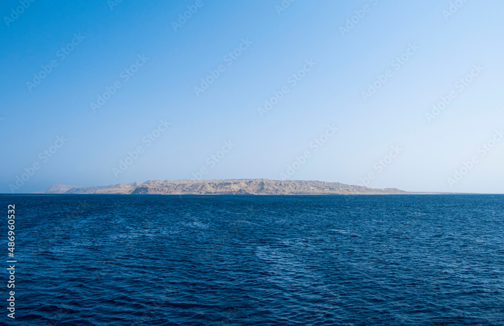 Lonely island in the Red sea. Blue sea water horizon line. Seawater background. Blue sea with little waves texture. Seawater surface texture
