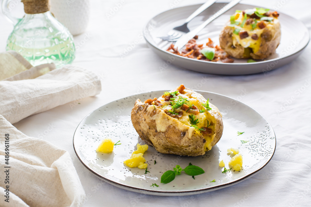 Twice-baked potatoes in their skins with cheese and bacon crumbs on plates on a wooden table. Flexitarian Diet