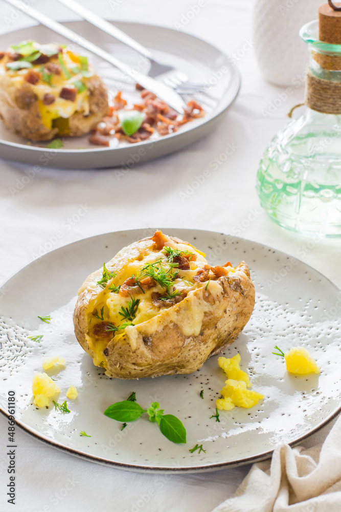 Appetizing twice-baked potatoes in their skins with cheese and bacon crumbs on plates on a wooden table. Flexitarian Diet. Close-up. Vertical view Appetizing twice-baked potatoes in their skins with cheese and bacon crumbs on plates on a wooden table. Flexitarian Diet. Close-up. Vertical view