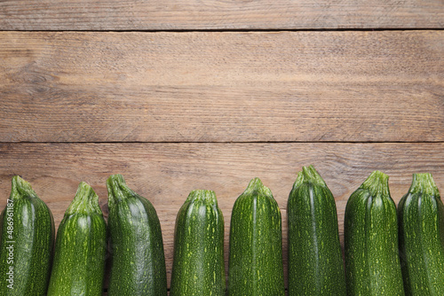 Raw ripe zucchinis on wooden table, flat lay. Space for text