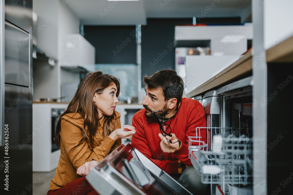Obraz premium Young couple buying dishwasher in store.