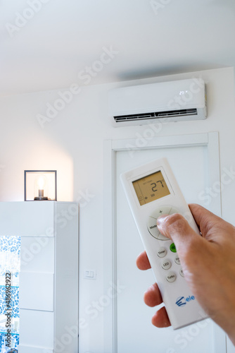Person turning on air conditioner to heat house with hot air. Increases in bills, electricity, gas, electricity.