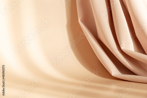 Abstract 3d studio with draping silk fabric and shadow on cream beige pastel monochrome background for cosmetic product presentation. Empty room, scene, podium or stand with copy space.