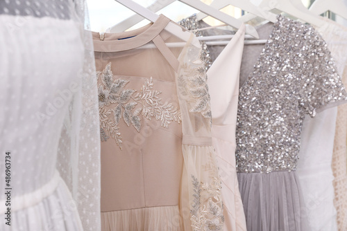 Hangers with different beautiful dresses in atelier, closeup