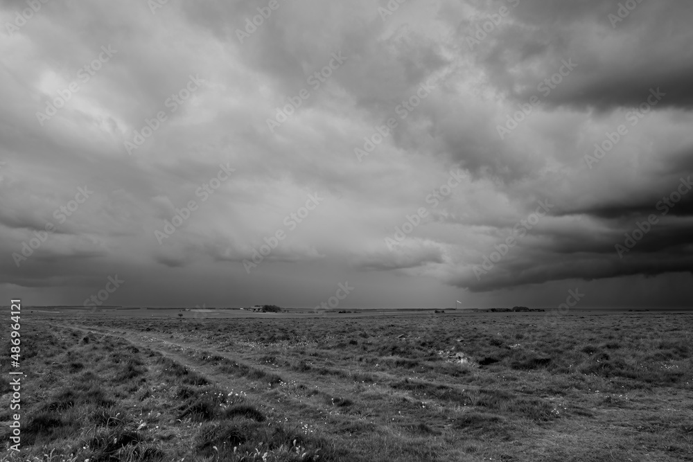 a foreboding dramatic dark grey thunder storm cloud sky over an open grass airfield and grass meadows