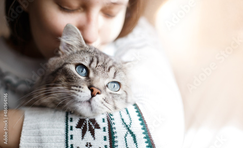 Smiling woman at home holding her lovely  fluffy cat. Gray tabby cute kitten with blue eyes. Pets and lifestyle concept. photo