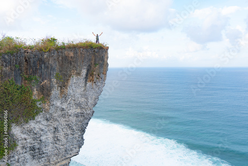 a man standing on a cliff watching the ocean photo