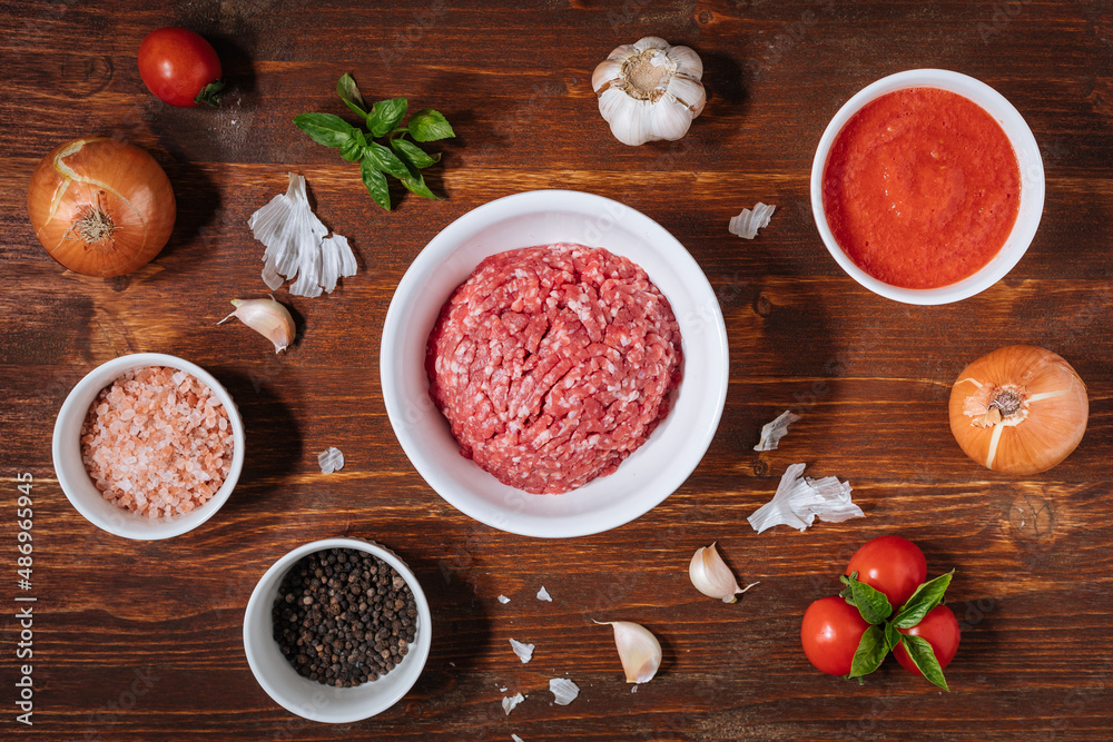 Meatballs in tomato sauce with basil on top. Bright background with ingredients in blurry background. This meal is called Kofte in Turkey and Cufte in Balkans. International meatball day. Meatballs in tomato sauce with basil on top. Bright background with ingredients in blurry background. This meal is called Kofte in Turkey and Cufte in Balkans. International meatball day.