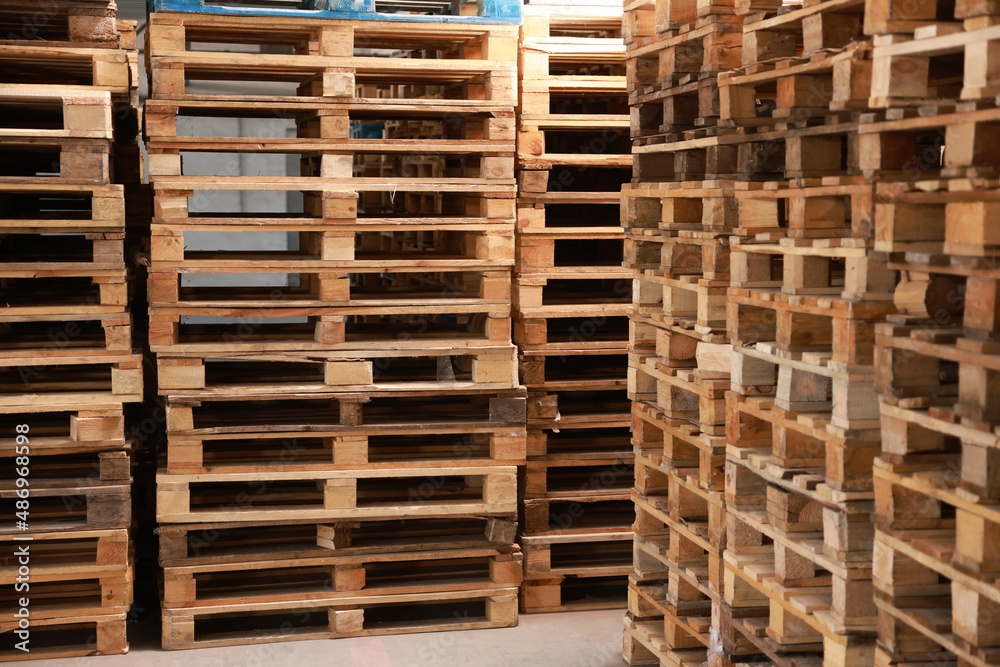 Many empty wooden pallets stacked in warehouse