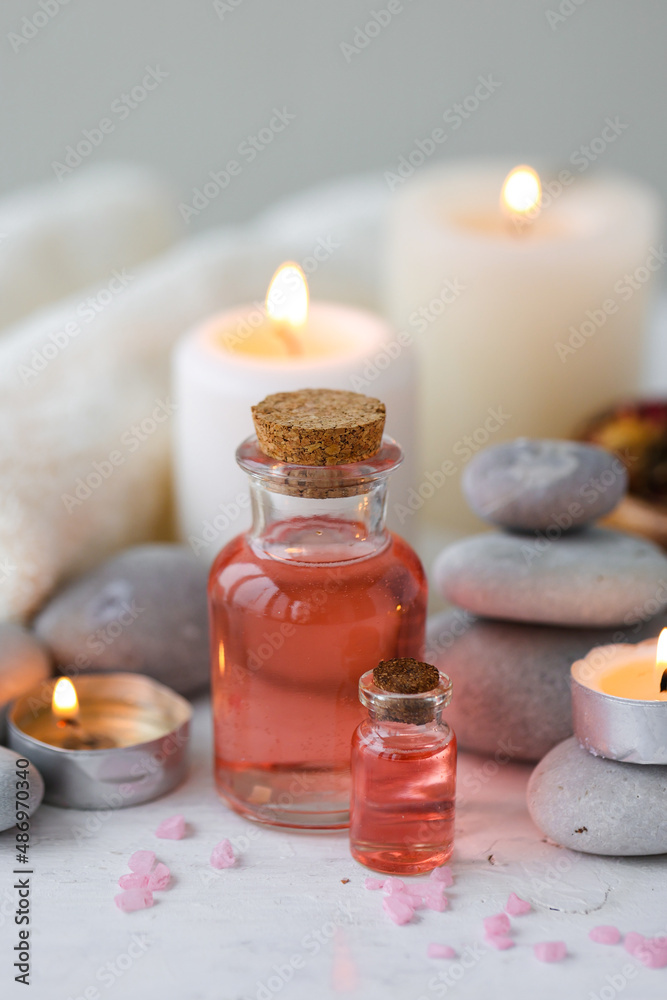 Concept of spa treatment in salon. Natural organic oil, towel, candles as decor. Atmosphere of relax, serenity and pleasure. Anti-stress and detox procedure. Luxury lifestyle. White wooden background Concept of spa treatment in salon. Natural organic oil, towel, candles as decor. Atmosphere of relax, serenity and pleasure. Anti-stress and detox procedure. Luxury lifestyle. White wooden background