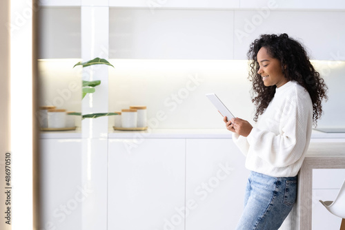 African American Girl using iPad tablet at home pressing finger, reading social media internet, typing text or shopping online. Freelancer Remotely working online at home