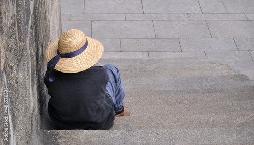 Mendigo sentado numas escadas à espera de uma esmola - sem abrigo com um chapéu - escadas em pedras - degraus photo
