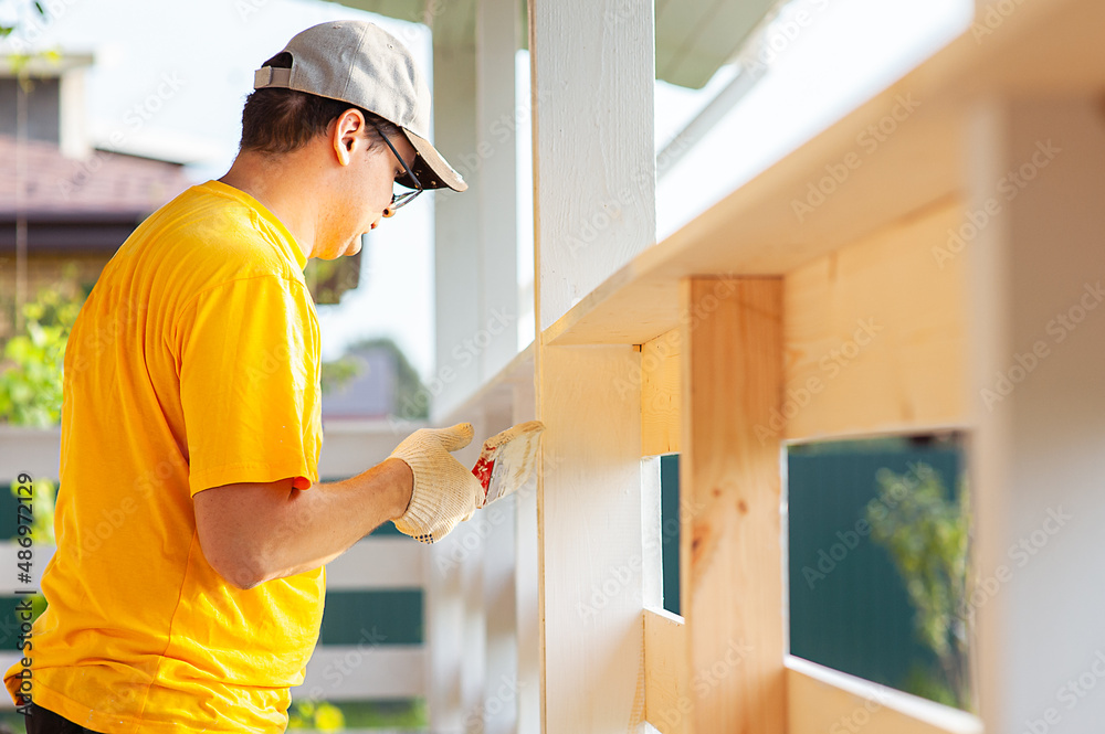 custom made wallpaper toronto digitalA man in a bright yellow T-shirt and cap holds a brush in his hand and paints the boards on the porch of the house with white paint