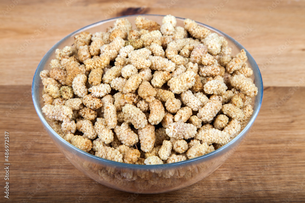 Dried mulberry in glass bowl on wooden background Dried mulberry in glass bowl on wooden background
