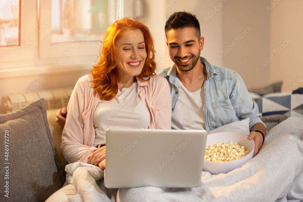 Beautiful couple watching movie on laptop at home Beautiful couple watching movie on laptop at home