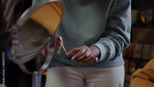 A young lady is drawing her friend a greasepaint photo