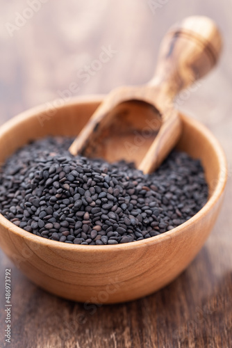 Bio natural black sesame seeds on wooden bowl.