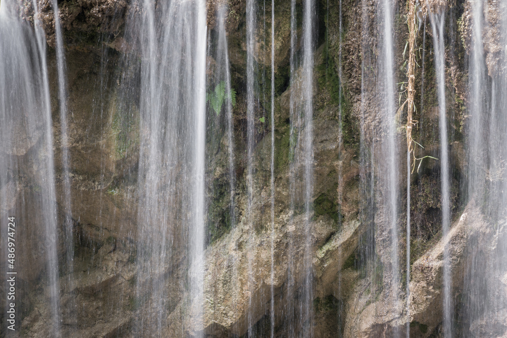 Scenic, close-up view of water cascade of a waterfall, splashing down the wet, yellow, vertical cliff Scenic, close-up view of water cascade of a waterfall, splashing down the wet, yellow, vertical cliff