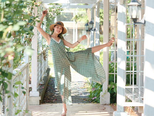 Portrait of young Asian woman posing with open legs and arms in sunny day, beautiful Chinese girl with green hairs in green dress dancing in garden carefreely, full length shot. photo