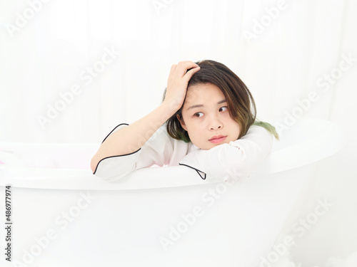 Portrait of young Asian woman sitting in bathtub and smiling  beautiful Chinese girl with green hairs rest in bathtub have a day dream.