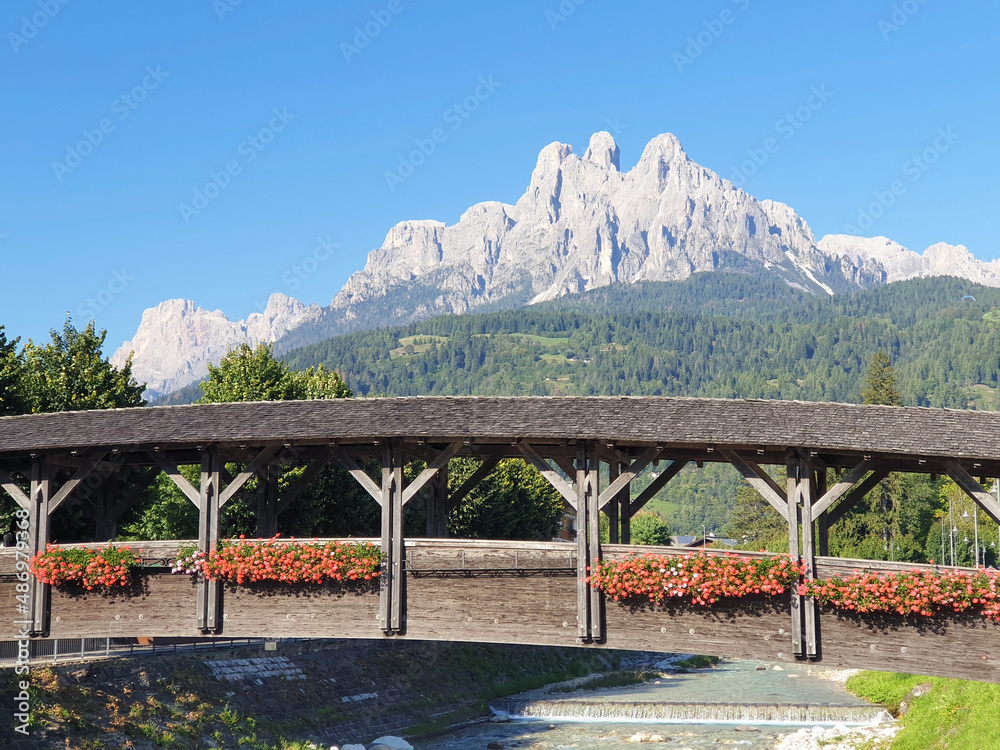 Dolomites mountains panorama with wooden bridge and river.