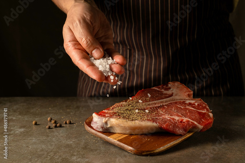 Raw T-bone steak with coarse salt and black pepper