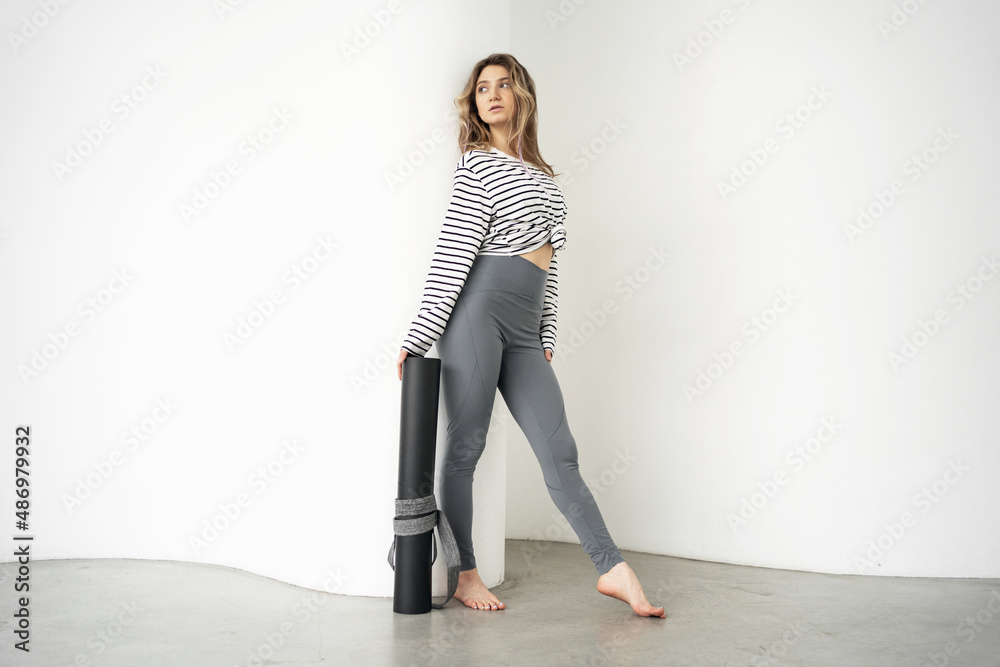 Yoga trainer woman holding mat posing in sports comfortable clothes. Lifestyle concept Yoga trainer woman holding mat posing in sports comfortable clothes. Lifestyle concept