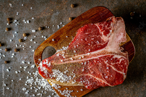 Raw T-bone steak cooking on stone table
