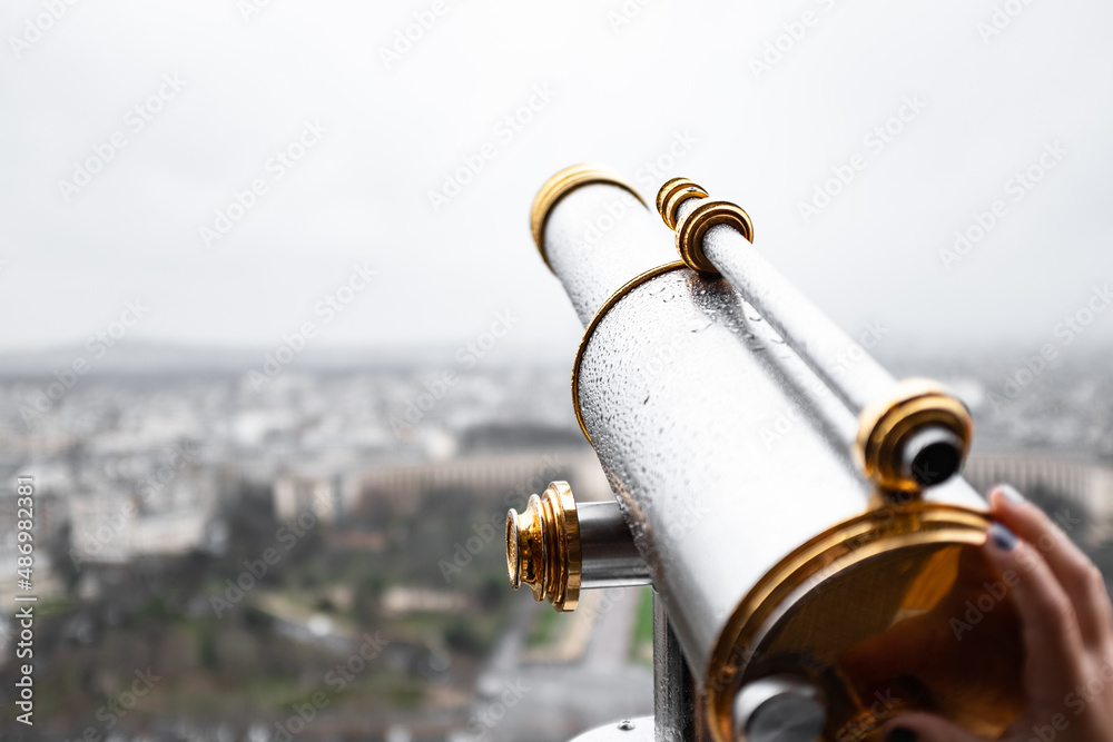 Old metal monocular with rain drops on a blurry urban landscape