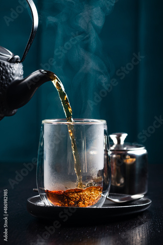 hot tea is poured into a glass with steam