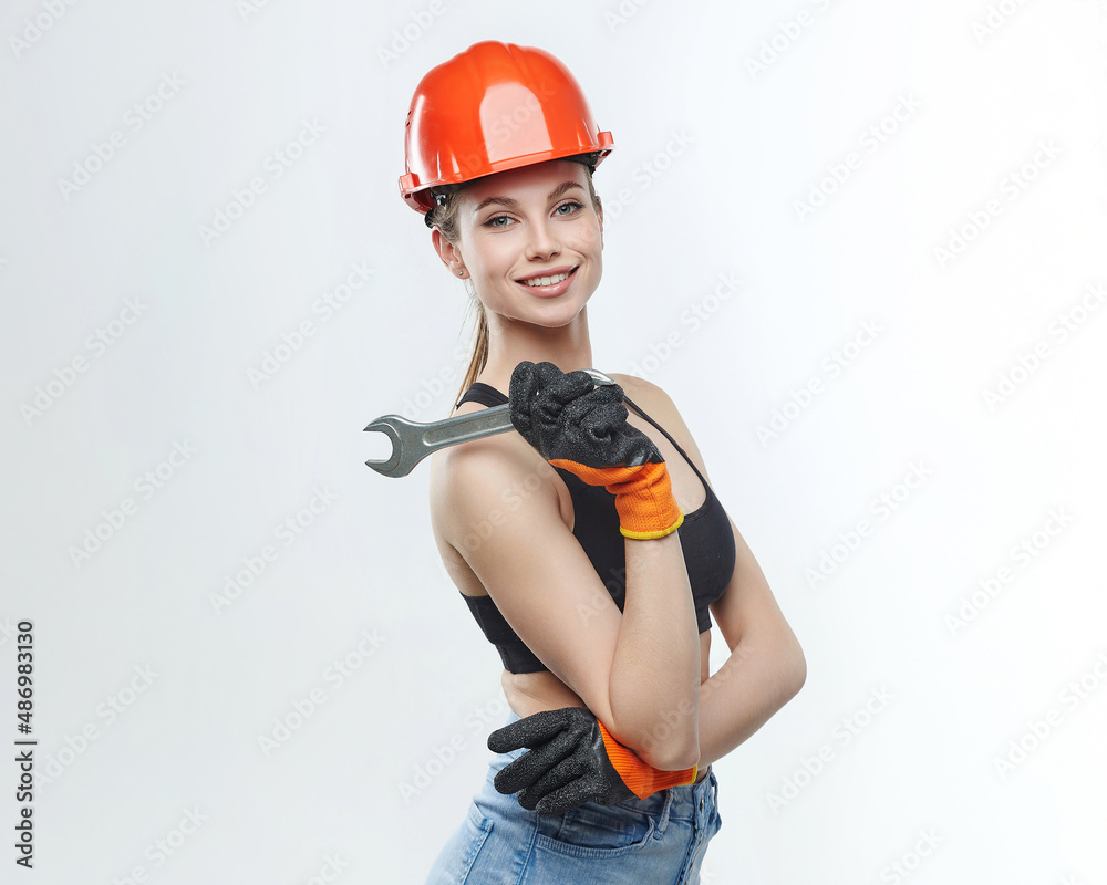 attractive blonde in an orange protective helmet and a wrench in her hands.