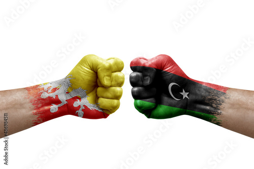 Two hands punch to each others on white background. Country flags painted fists, conflict crisis concept between bhutan and libya