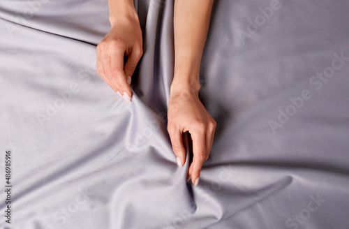 Woman touching soft silver fabric  top view