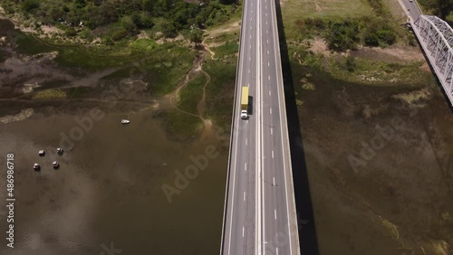 Aerial tracking shot of yellow truck driving on Barra de Santa Lucia Bridge during sunny day in Uruguay photo