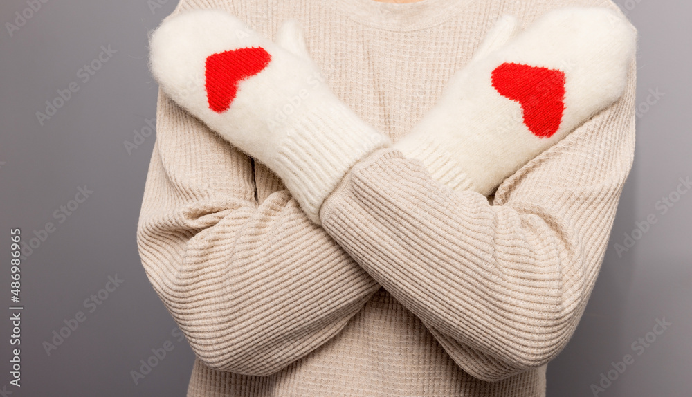 Woman in white sweater and mitts with red hearts with hands crossed