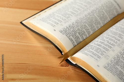 Open Bible with bookmark on wooden table, closeup