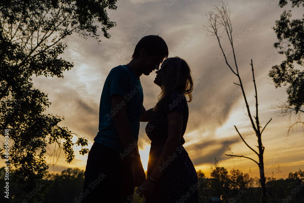 The silhouette of a young couple loving each other on the background of the sunset.