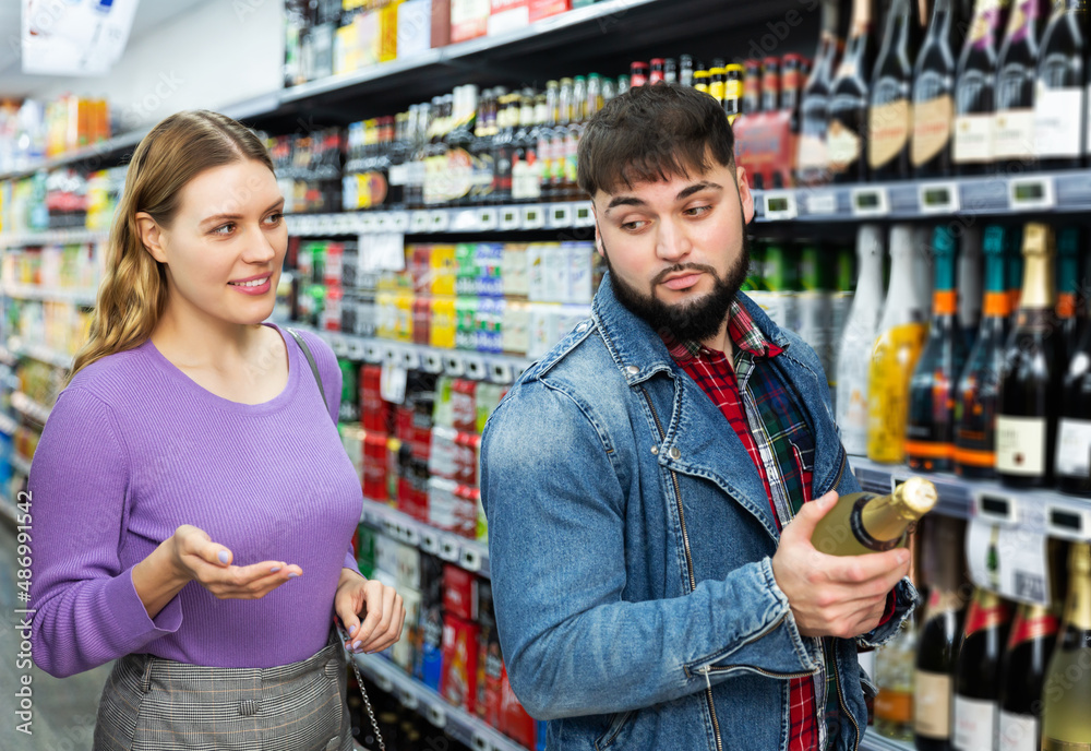 Happy married couple chooses alcohol in a supermarket