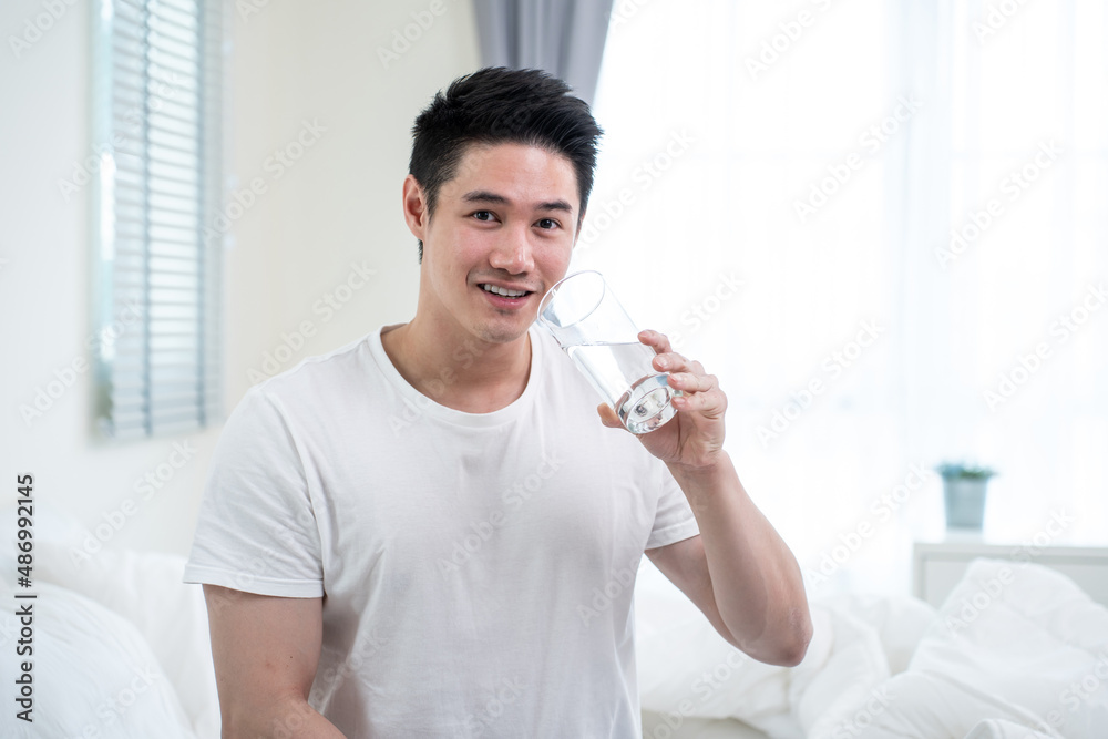 Portrait of Asian active strong man holding clean water in bedroom. Portrait of Asian active strong man holding clean water in bedroom.