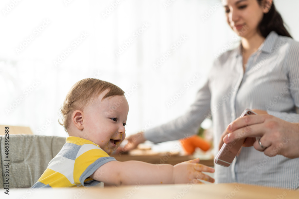 Young mother and baby boy video call online with family while eating. Young mother and baby boy video call online with family while eating.