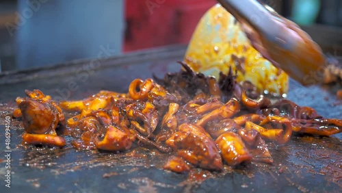 A chef is cooking spicy grilled baby octopus, korean street food, frying squid